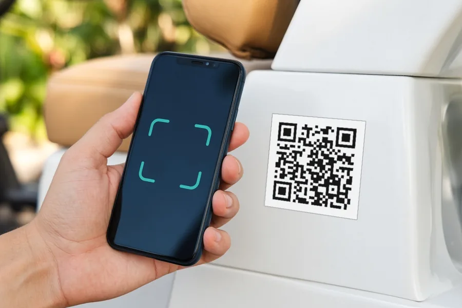 A hand holding a phone up to the QR label on the side of a golf cart to report a problem.
